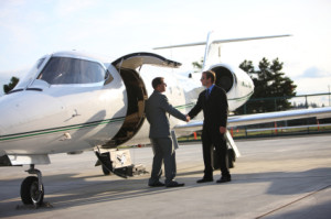 Businessmen shake hands by corporate jet